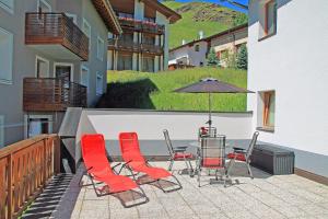 a patio with a table and chairs and an umbrella at Chasa Arlu in Samnaun