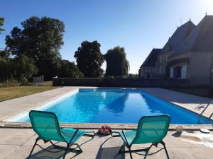 a swimming pool with two chairs and a house at Château de Mongazon in Saint-Franchy