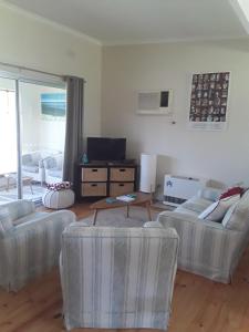 a living room with two couches and a tv at Bay Bell Cottage in Saint Leonards