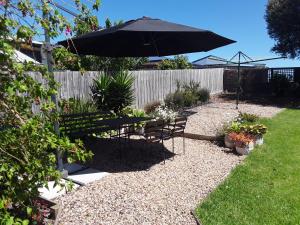 a garden with an umbrella and a table and chairs at Bay Bell Cottage in Saint Leonards +14 photos