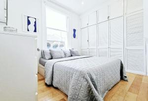 biała sypialnia z łóżkiem i oknem w obiekcie Eden Luxury Apartments w Londynie