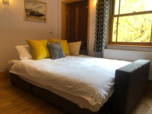 a large bed with yellow and grey pillows and a window at Lazy Daze Cottage in Horsham