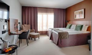 a hotel room with a large bed and a desk at Skara Konsthotell in Skara
