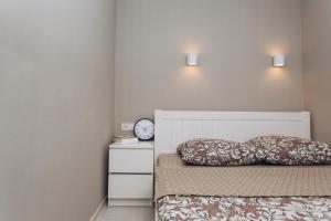 1 dormitorio con 1 cama con 2 almohadas y reloj en Apart-hotel I. Sirko New Building 3 floor, en Sumy