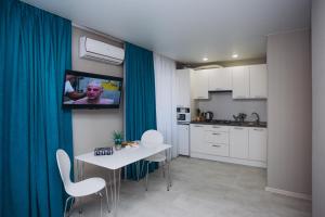 a kitchen with a table and a tv on a wall at Apart-hotel I. Sirko New Building 3 floor in Sumy