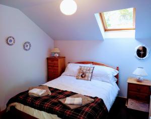 a bedroom with a bed with white sheets and a window at Granite Croft in Appin