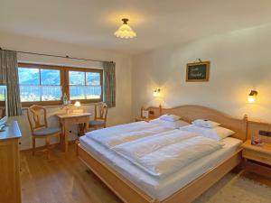 ein Schlafzimmer mit einem großen Bett, einem Tisch und Stühlen in der Unterkunft Rostalm in Berchtesgaden