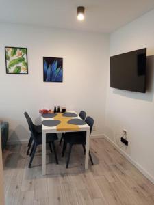 a dining room table with chairs and a flat screen tv at Apartament na Zakręcie in Szklarska Poręba