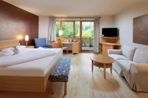 Habitación de hotel con cama y sala de estar. en Ayurveda Resort MANDIRA, en Bad Waltersdorf