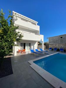 a villa with a swimming pool and blue chairs at Villa Maja in Cavtat