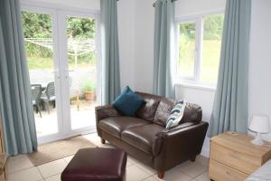 a living room with a leather couch in front of a window at Freshwater Bay Holiday Cottages in Pembroke