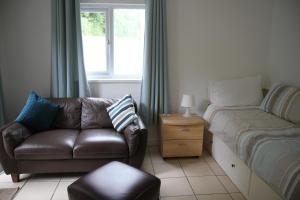 a living room with a couch and a bed and a window at Freshwater Bay Holiday Cottages in Pembroke