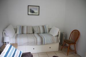 a bed with a striped blanket and a chair in a room at Freshwater Bay Holiday Cottages in Pembroke