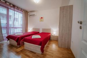 een slaapkamer met een rood bed en een raam bij Bella's Sea apartment-Beach, Sea garden ,Old Town, Free Parking, Free EVcharging Station in Varna