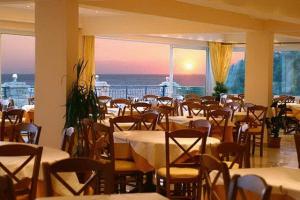 een restaurant met tafels en stoelen en uitzicht op de oceaan bij Aloha Hotel in Agios Gordios