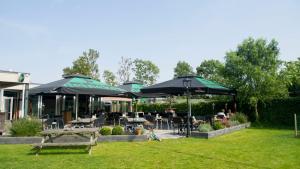 a patio with tables and umbrellas in a park at Chaletparc Krabbenkreek - Chalet 266 in Sint Annaland