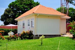 a small white house with an orange roof at Victoria Lake View Guesthouse & Safaris in Entebbe