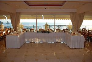 un salón de banquetes con mesas y sillas blancas en Aloha Hotel, en Agios Gordios