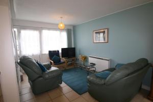 a living room with two chairs and a television at Freshwater Bay Holiday Cottages in Pembroke