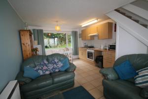 a living room with a couch and a kitchen at Freshwater Bay Holiday Cottages in Pembroke