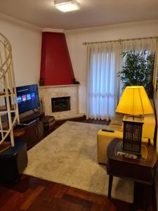 uma sala de estar com um sofá e uma mesa com um candeeiro em Apartamentos Centrinho Capivari - Condomínio Recanto do Boticário em Campos do Jordão
