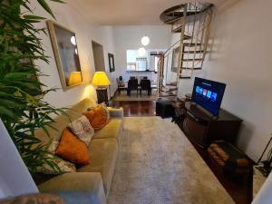 uma sala de estar com um sofá e uma televisão de ecrã plano em Apartamentos Centrinho Capivari - Condomínio Recanto do Boticário em Campos de Jordão