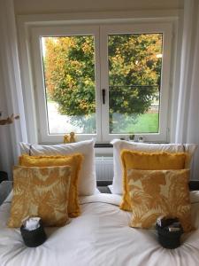 1 cama con sábanas y almohadas blancas frente a 2 ventanas en Villa van Brienen - Studio, en Dilsen-Stokkem