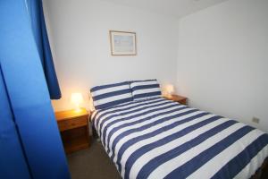 a bedroom with a blue and white striped bed and two lamps at Freshwater Bay Holiday Cottages in Pembroke