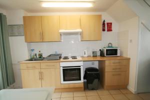 a small kitchen with wooden cabinets and a microwave at Freshwater Bay Holiday Cottages in Pembroke