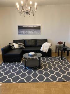 a living room with a black couch and a blue rug at Viihtyisä asunto keskustassa palvelujen lähellä in Heinola