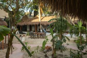 a house with a thatched roof with a table and chairs at Kinta Kan Cabañas Hotel Playa del Carmen in Playa del Carmen