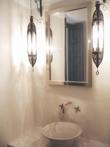baño con lavabo, 2 lámparas de araña y espejo en Riad Dar-K, en Marrakech