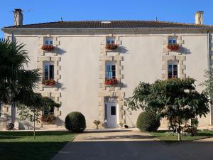 Mougon的住宿－Montaillon Chambres d'Hôtes，白色的大建筑,窗户上摆放着鲜花