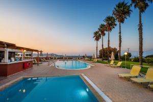 una piscina con sedie e palme di Jonathan Studio Apartments a Tigaki