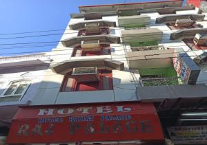 wysoki biały budynek z balkonem i czerwonym znakiem w obiekcie Hotel Raahat Palace w mieście Adźmer