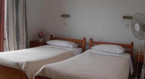 
two beds in a room with a white bedspread at Harry's Bar & Apartments 2 in Acharavi
