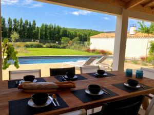 uma mesa de madeira num pátio com uma piscina em Villa Vintour em Malaucène