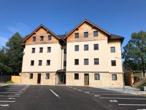 a large white building in a parking lot at Apartman Jelen in Deštné v Orlických horách