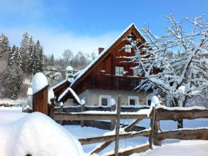 Ferienhaus "Zur alten Schmiede" في Mariahof: كابينة خشبية في الثلج مع سياج