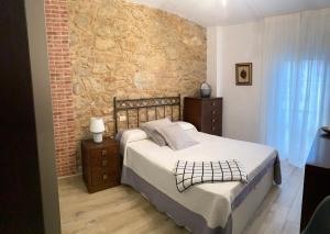 ein Schlafzimmer mit einem Bett und einer Ziegelwand in der Unterkunft CASA SAN JURJO in Kap Finisterre