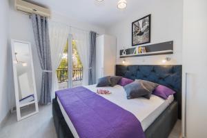 a bedroom with a large bed with purple sheets and a window at Luxury Apartments Tafra in Lokva Rogoznica