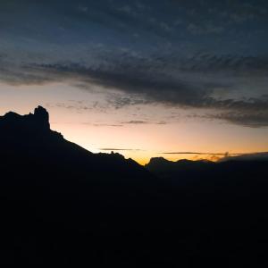 a sunset in the mountains with a silhouette of a mountain at Ecoartejeda CAVE HOUSE in Tejeda