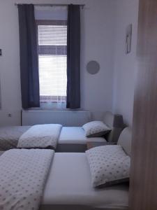 three beds in a room with a window at Studio apartman Ela in Travnik