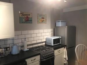 a kitchen with a stove and a microwave and a refrigerator at Blue Sky Cottage in Matlock