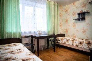ジヴェエヴォにあるDiveevskiy Guest Houseのベッド2台、テーブル、窓が備わる客室です。