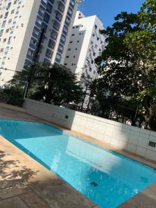a blue swimming pool in front of tall buildings at Apartamento Boutique Good Vibes in Guarujá