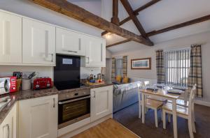 una cocina con armarios blancos y una mesa con sillas. en Brampton Holiday Homes - The Mews Apartment en Brampton