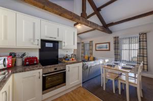a kitchen with white cabinets and a table with chairs at Brampton Holiday Homes - The Mews Apartment in Brampton