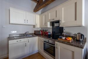 cocina con armarios blancos y encimera en Brampton Holiday Homes - The Mews Apartment en Brampton