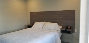 1 dormitorio con cama blanca y cabecero de madera en Maxim III Motel, en Houston